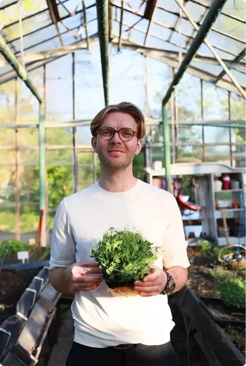 Photo shows the owner of MP Seeds holding pea microgreens